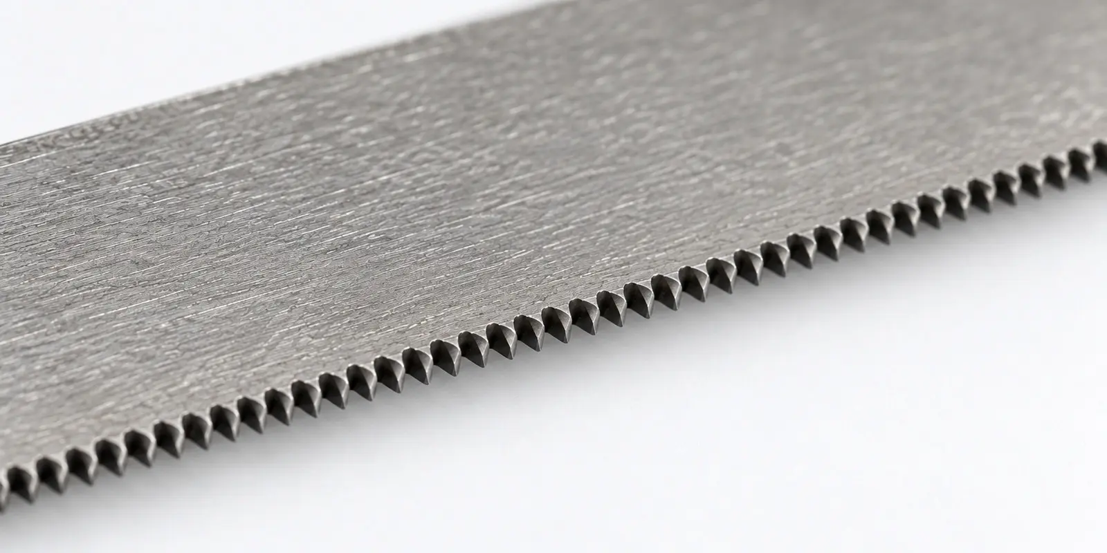 Illustrative close-up of a hand hacksaw blade tooth edge; not a measured TPI comparison